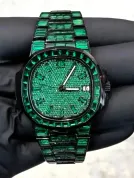 VVS1 Moissanite "Emerald" Flood: Fully handset with D-Color VVS1 Moissanite stones in a rare emerald green shade that passes thermal diamond testers. Baguette-Cut Bezel & Band: Features high-grade baguette-cut stones on the bezel and every link of the band for a clean, architectural shine. Stealth Black PVD Finish: Crafted from 316L stainless steel with a premium black PVD coating for a scratch-resistant, high-end matte-to-gloss look. Micro-Pave Dial: The watch face is fully flooded with round-cut green moissanite stones, offering 360-degree light refraction. Precision Date Function: Includes a functional date window at 3 o'clock, blending tactical utility with high-jewelry aesthetics.